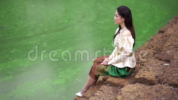 在池塘边穿着泰国裙子的快乐美女的慢动作视频的预览图