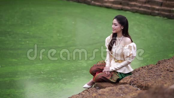 在池塘边穿着泰国裙子的快乐美女的慢动作视频的预览图