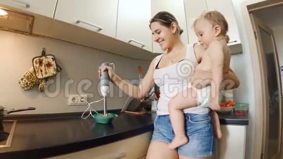 年轻女子在厨房做饭抱着她的小儿子视频的预览图
