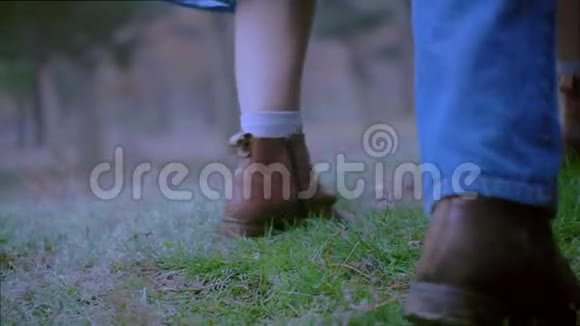 穿着牛仔裤和靴子在草地上行走的女性和男性的腿紧贴着视频的预览图