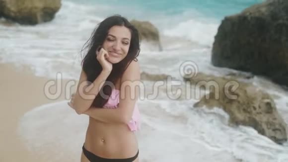 慢镜头穿着泳装的快乐女孩的肖像在海滩上放松背景上有美丽的波浪稳定的镜头视频的预览图