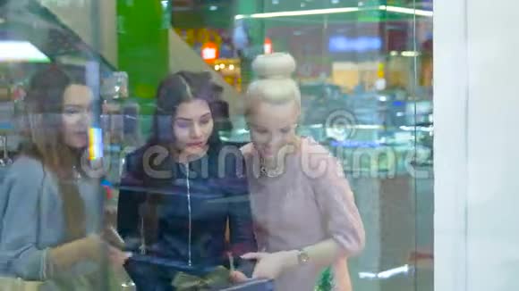 女士们站在商场的购物窗口旁有感情地讨论购物视频的预览图
