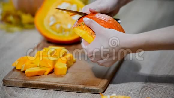 男人在木制厨房桌子上清洗南瓜男性准备切橙色南瓜片视频的预览图