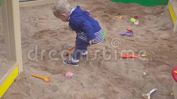 儿童游戏小男孩在沙箱里挖微笑和触摸沙子视频的预览图
