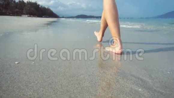 日落时光着脚在海滩上散步的女人女人在海边的沙滩上散步视频的预览图