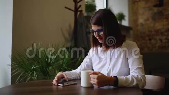 一个漂亮的学生女孩在校长里唱咖啡并在电话上给她的男朋友写短信a行视频的预览图