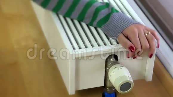 女孩温暖的手在家里的现代散热器视频的预览图