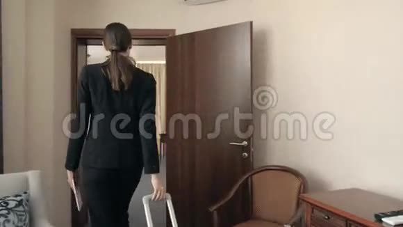 年轻的商务女性拿着一个手提箱打开旅馆房间的门走进房间视频的预览图
