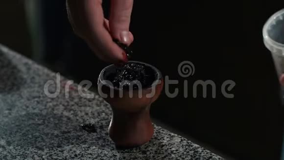 一个男人的特写把水果烟草放在碗里作为一个钩子在一个钩子酒吧视频的预览图