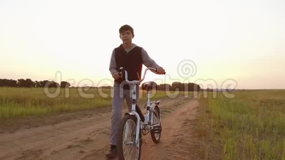 男孩少年骑自行车在大自然的道路上少年骑自行车到户外旅行视频的预览图