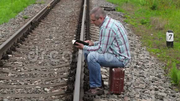 坐在铁路附近的手提箱和看书的人视频的预览图