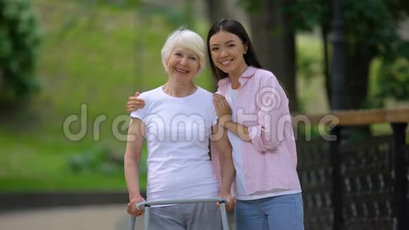 志愿者和残疾老妇人在医院公园里对着镜头微笑视频的预览图