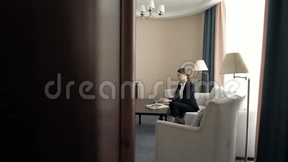 一位年轻漂亮的商务女性在酒店的男式西装房里用电脑工作视频的预览图