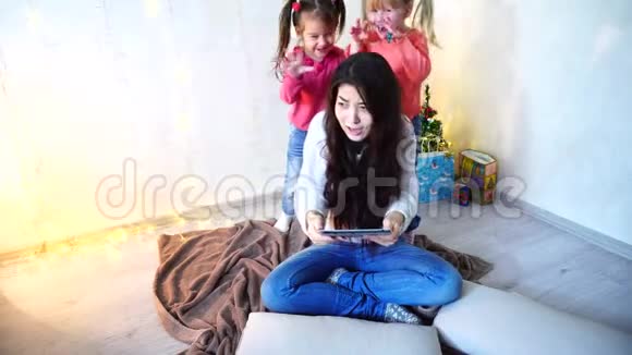 与最小的女孩坐在房间的地板上墙上挂着花环和视频的预览图