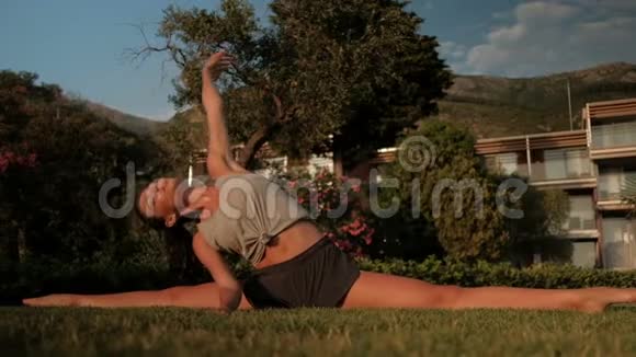 坐在麻绳上的迷人女人把手伸在草地上视频的预览图