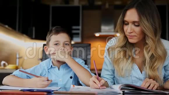 微笑的妈妈帮儿子做作业口述课文帮你写坐在厨房的桌子旁视频的预览图