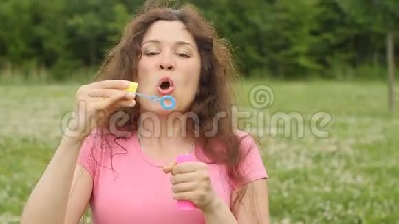 在公园里吹肥皂泡的年轻女子视频的预览图