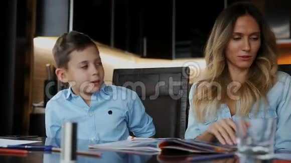 微笑的妈妈帮儿子做作业口述课文帮你写坐在厨房的桌子旁视频的预览图