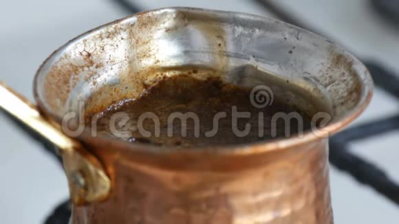在一个铜制的土耳其煮黑咖啡然后在煤气炉上煮咖啡师在家附近准备热饮视频的预览图