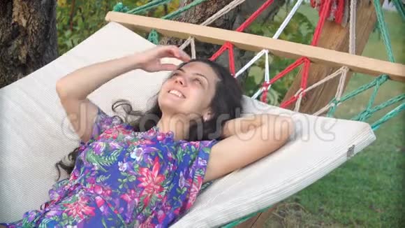 戴着帽子的浅黑色女人在热带海滩的吊床上放松和做梦视频的预览图