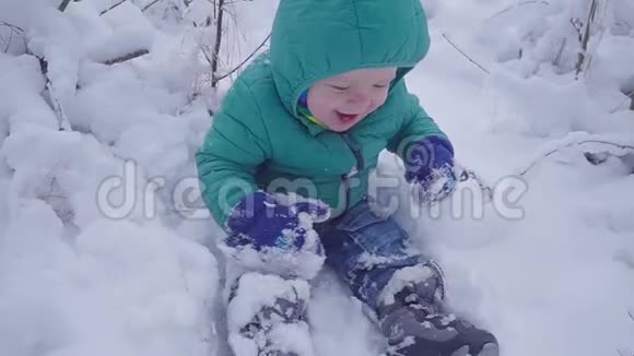 快乐的一岁男孩坐在冬天的森林里笑用万向节制作视频的预览图
