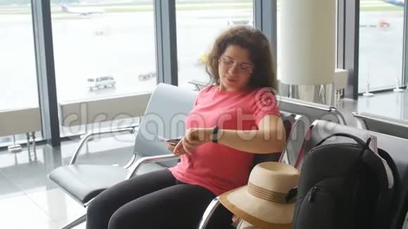 在国际机场看智能手机和等待航班的年轻女子视频的预览图