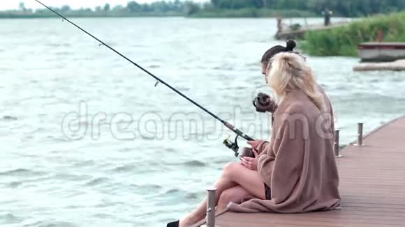 一对美丽的情侣在湖边钓鱼一个男人坐在码头上一对恋人一对恋人坐在一起视频的预览图