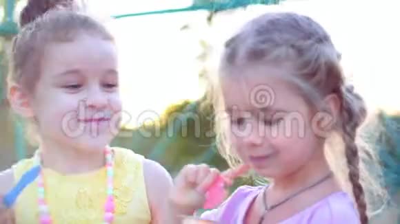 两个小女孩卷曲着漂亮的头发蓝眼睛拿着勺子吃着冰激凌面带微笑地看着对方视频的预览图