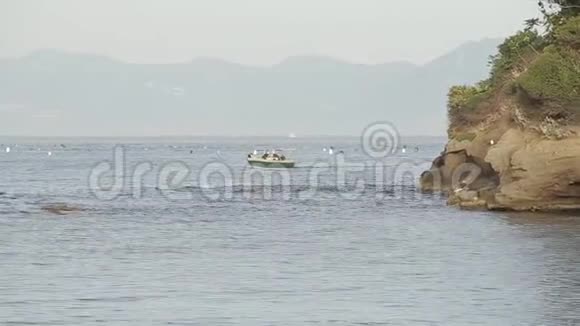 一艘小船沿着大海航行在一个有山的岛屿的背景上视频的预览图