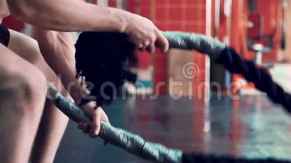 在健身房用绳子锻炼胳膊和肩膀的年轻人视频的预览图