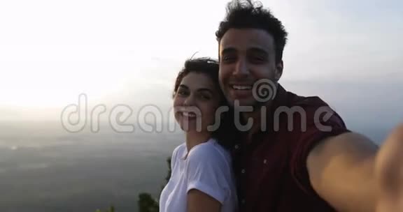 登上山顶的情侣在日出时自拍西班牙男人和女人幸福的微笑视频的预览图