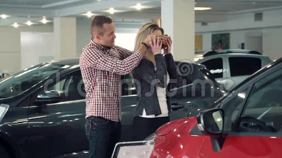 慢动作男人在汽车经销商给妻子或女朋友带来惊喜展示新车视频的预览图