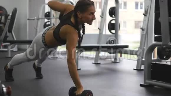 年轻的健身妇女在交叉健身馆做哑铃排活泼的女孩锻炼举重美丽的女人视频的预览图