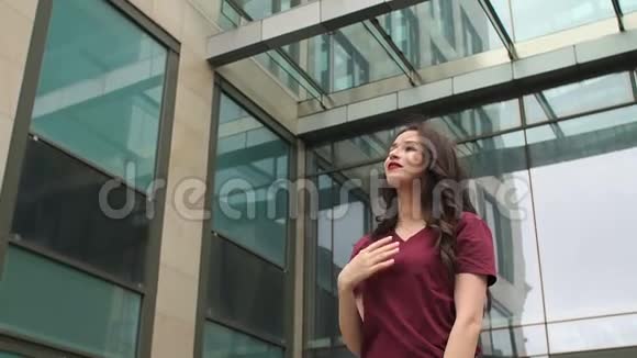 站在玻璃大楼附近的长发女孩视频的预览图
