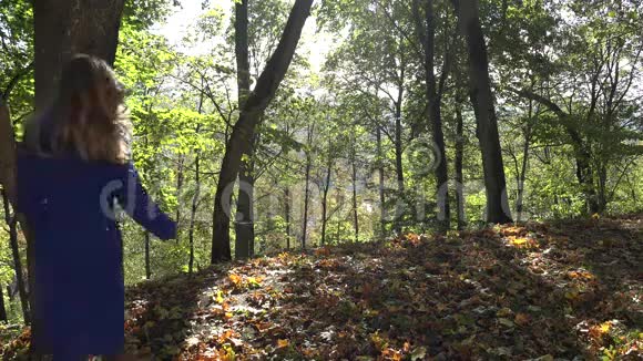 阳光明媚的一天穿着蓝色外套的年轻女子在秋天的公园4K视频的预览图