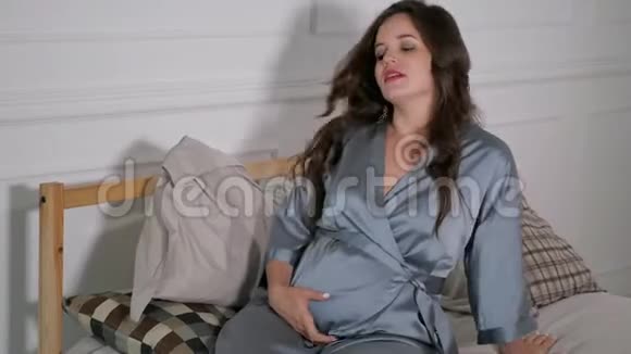 美丽的孕妇在床上拥抱视频的预览图