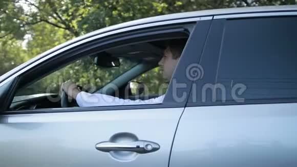 英俊的年轻人在乡村公路上开车视频的预览图