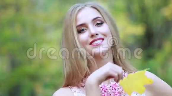 秋天公园里美丽的女人用黄色的枫叶遮住她的脸视频的预览图