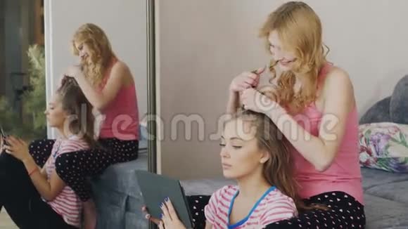 两个年轻的女人在家放松享受平板电脑辫子帕贾玛派对女友视频的预览图