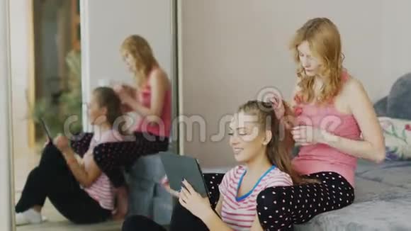 帕贾马派对女朋友两个年轻的女人在家放松享受平板电脑辫子视频的预览图