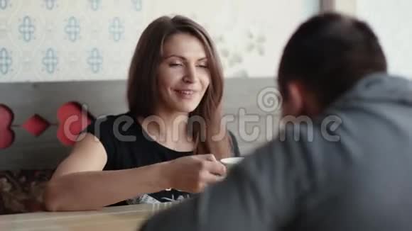 美丽的女人在咖啡馆里和男人交谈时有一杯咖啡茶和巧克力她微笑着享受着良好的陪伴视频的预览图