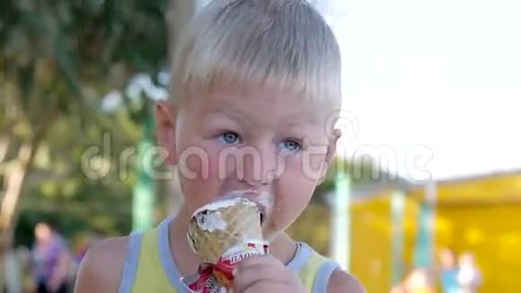 一个小白人男孩正在沙滩上吃冰淇淋特写视频的预览图