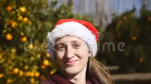 在花园里旋转的戴着圣诞帽的女人的镜头视频的预览图
