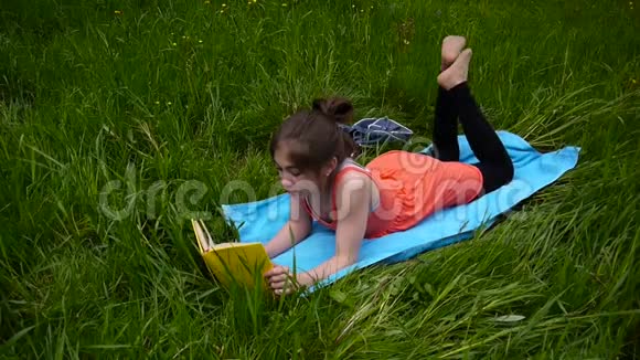 轻松的小女孩在田里看书可爱的少年躺在草地上视频镜头高清拍摄静态视频的预览图