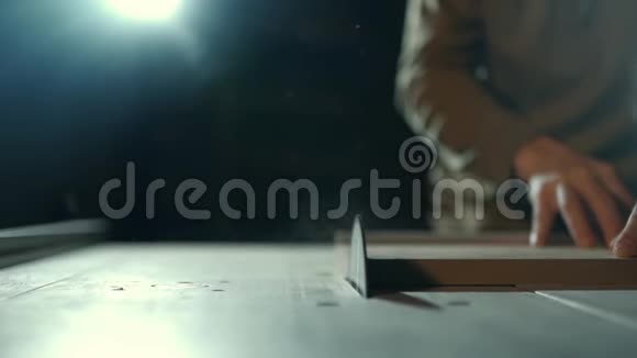 一个专业的木匠正在用一个特殊的电锯来切割一个长方形的木条在办公桌前工作视频的预览图