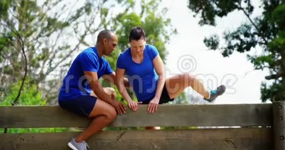 男教练协助健身女子在障碍课程4k期间爬过木墙视频的预览图