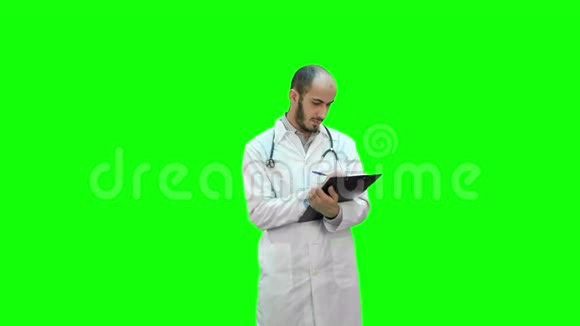 男医生穿着白色外套在绿色屏幕上填写处方表格铬键视频的预览图