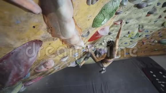 年轻女子攀岩者正在室内攀岩健身房攀岩苗条漂亮的女人做一些艰难的动作视频的预览图