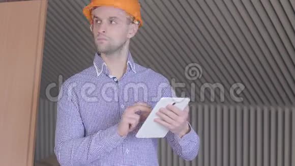 一位男性建筑设计师在正在施工的大楼里看着他的数码平板电脑屏幕视频的预览图