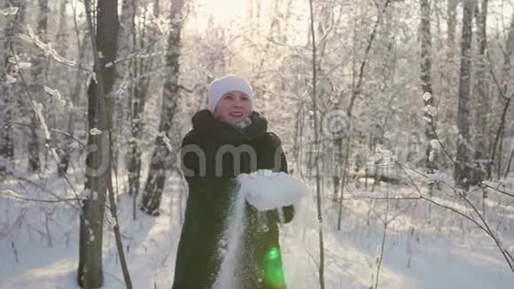 女孩走在冬天的树林里扔雪微笑笑在新鲜空气中游走视频的预览图
